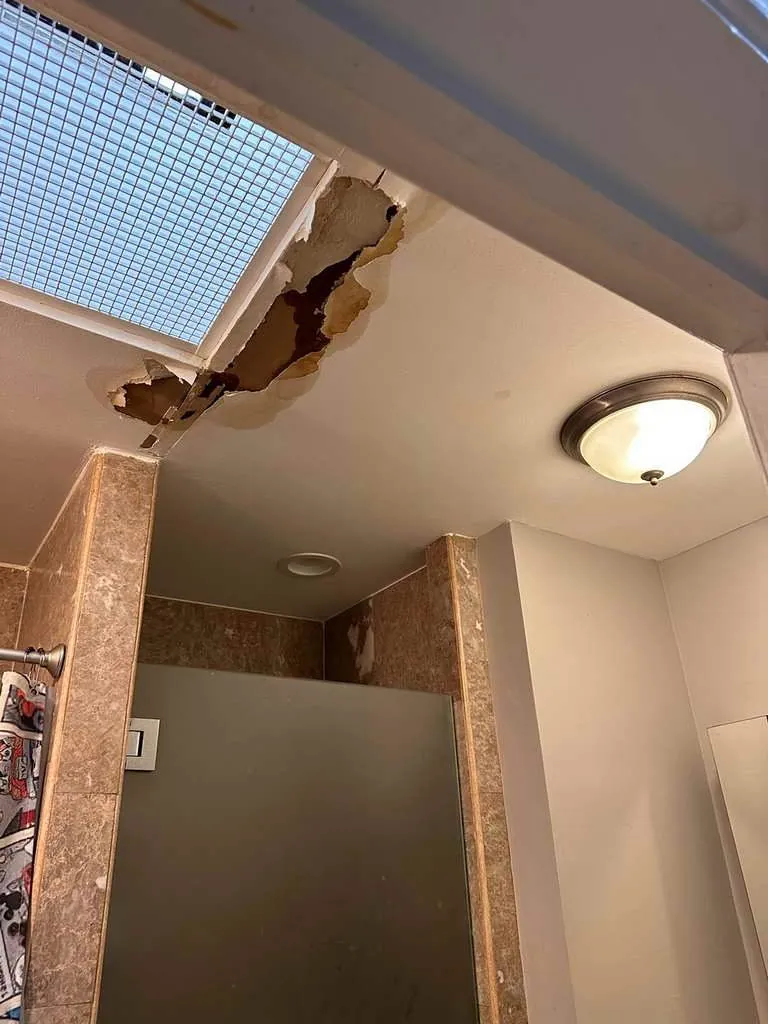 Water-damaged bathroom ceiling from a leak above, before repair, in Brooklyn