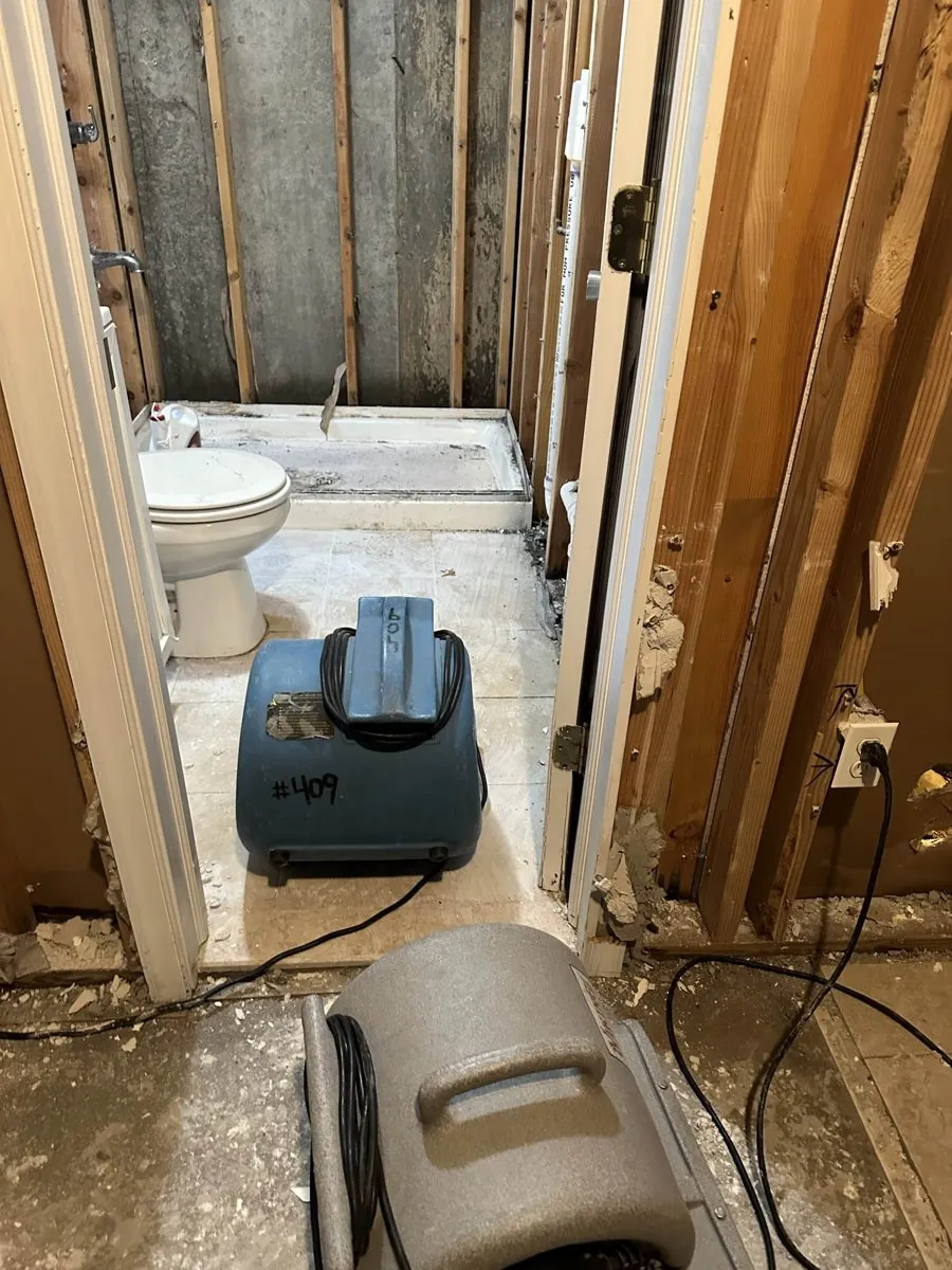 Air movers drying a gutted bathroom down to the studs after water damage in Brooklyn