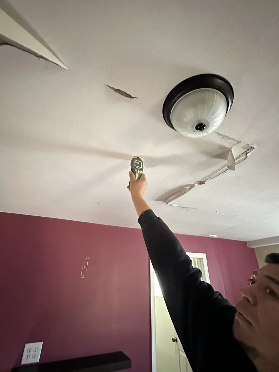 All Star Restoration technician checking a water-damaged ceiling with a moisture meter during a water damage job in Nassau County
